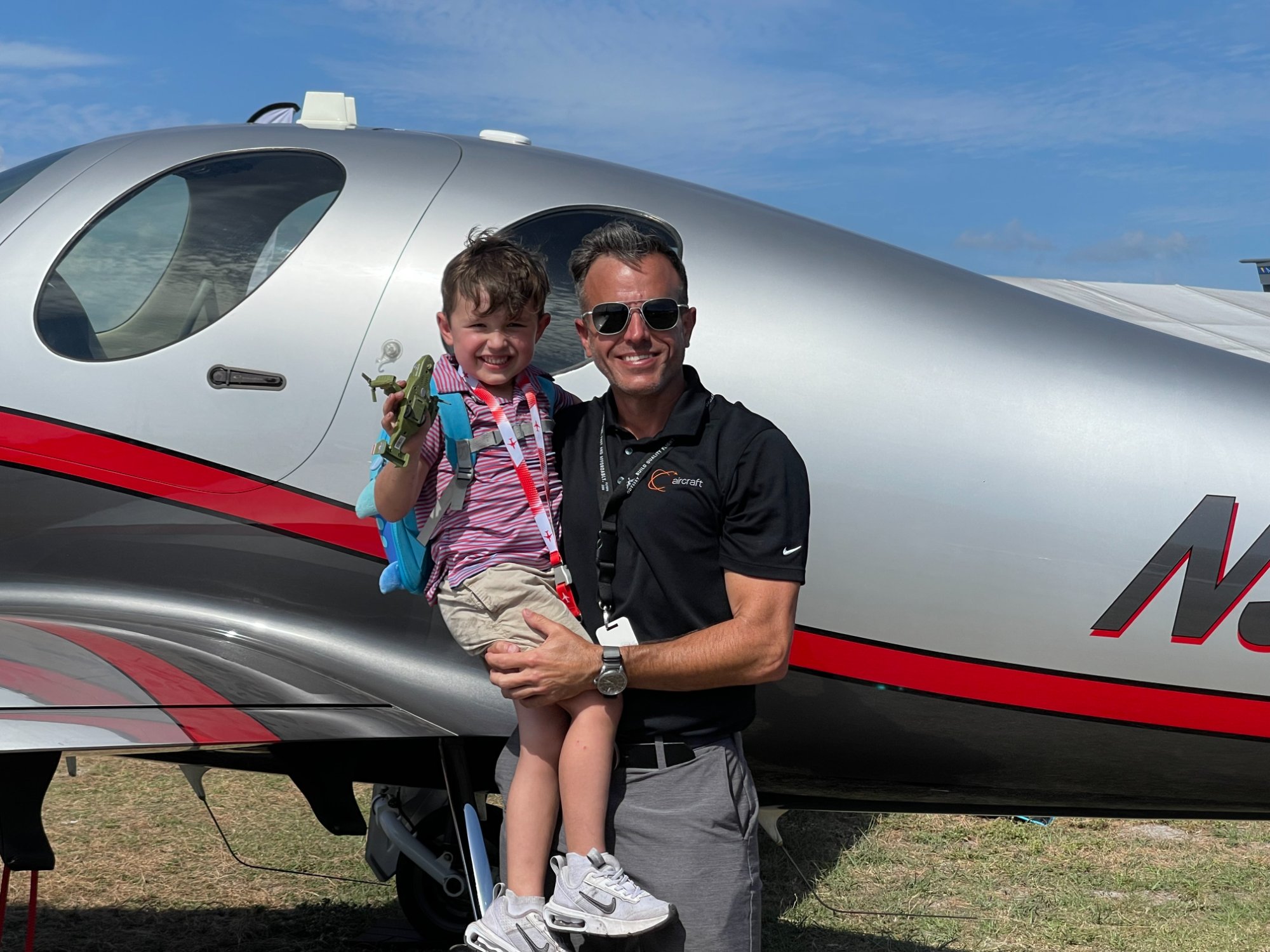 Josh Scheid, founder of Tyson Aviation, with his son at an airshow in front of a light sport aircraft